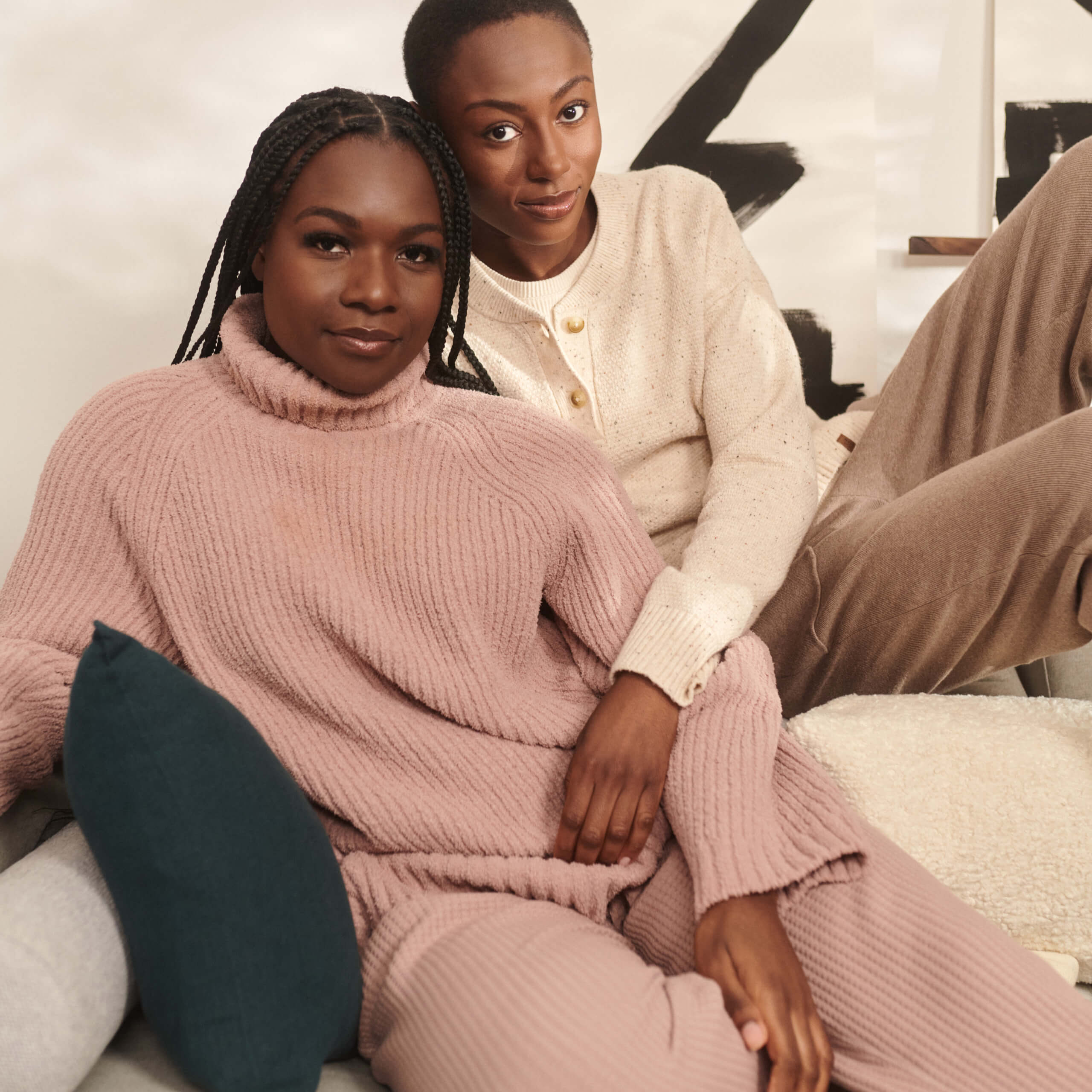 two woman wearing sweaters sitting